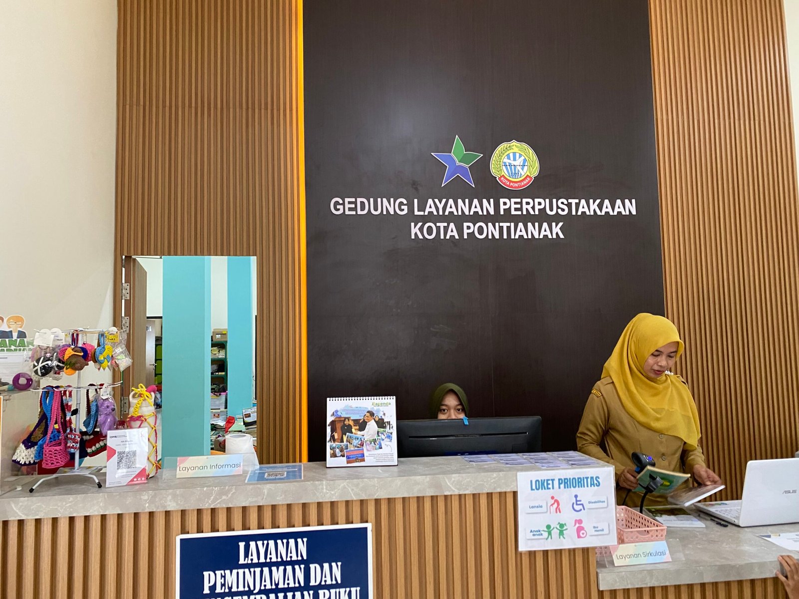 Petugas Disperpus Kota Pontianak saat berikan layanan peminjaman buku. Foto: Yulia Ramadhiyanti/Klikwartaku